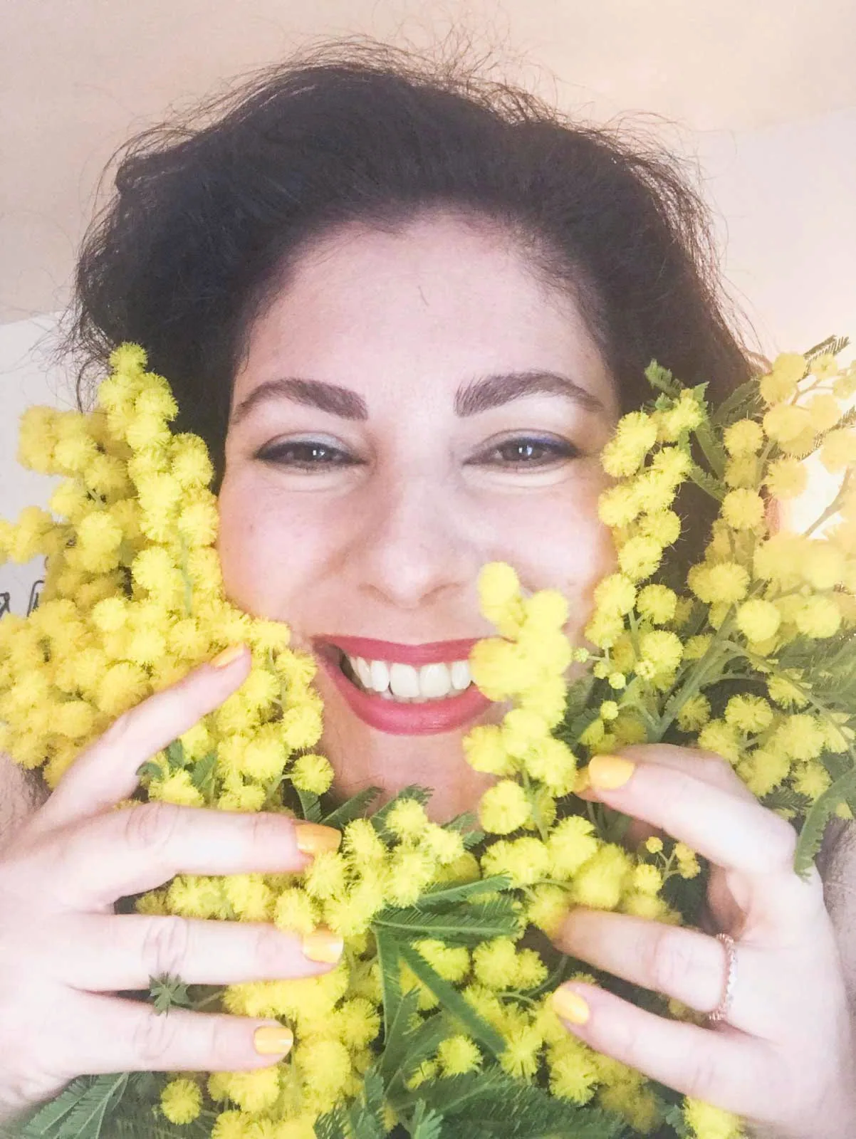Stefania D'Ippolito lacht hinter einem Strauss Mimosen